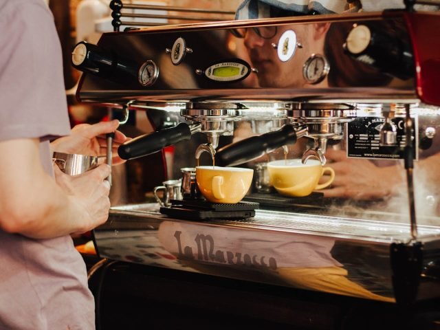 A barista pulling a fresh espresso shot on a professional coffee machine at a Brewtopia Coffee café